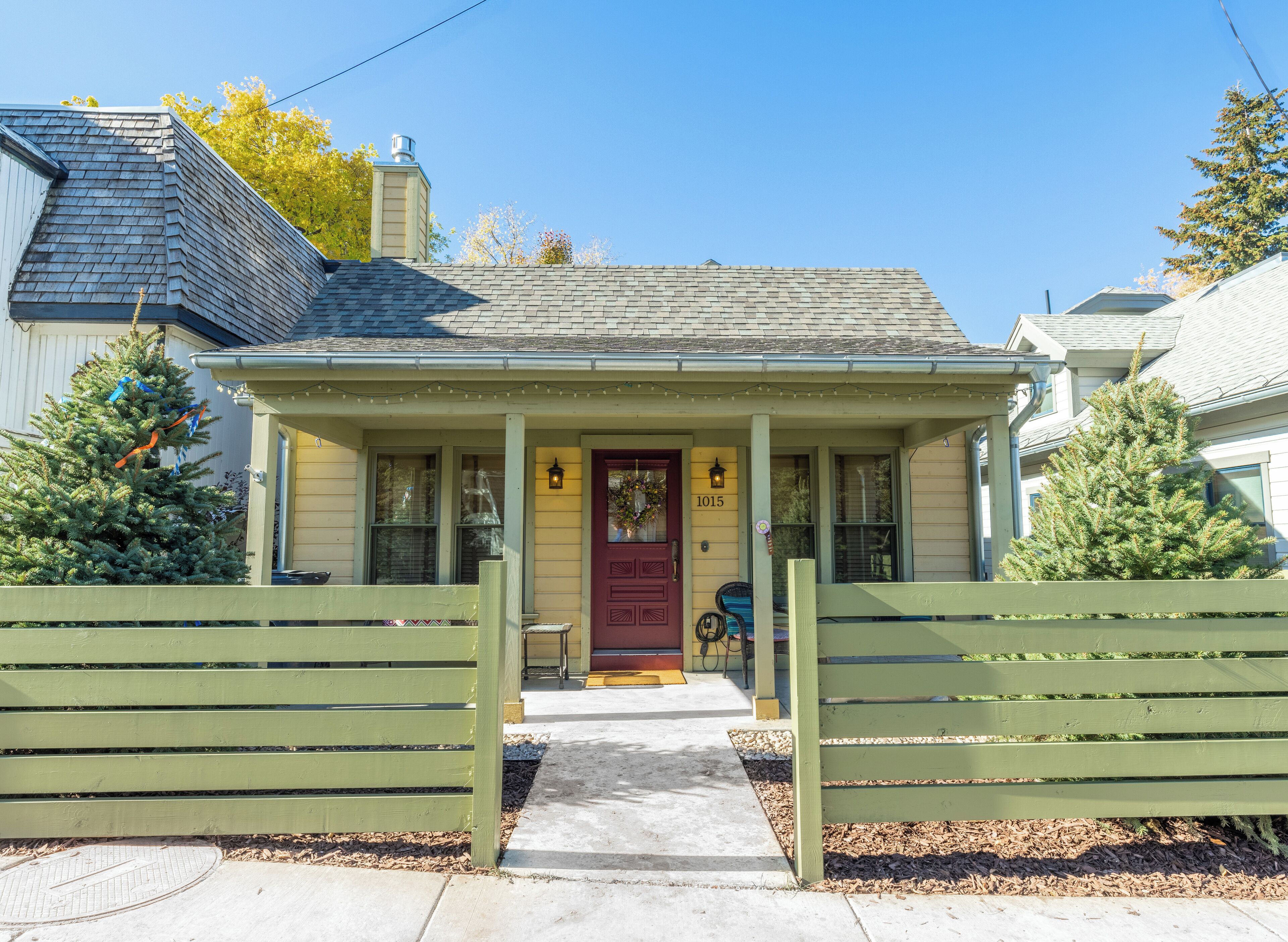A two-story house with a red door, number 1015, and a small porch with a bench.