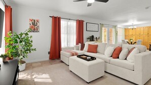 A living room with a sectional sofa, a coffee table, a potted plant, and a dining area in the background. - Sleeps 10 - Sparkling Pool - 7 mins to DT Chandler (Chandler)