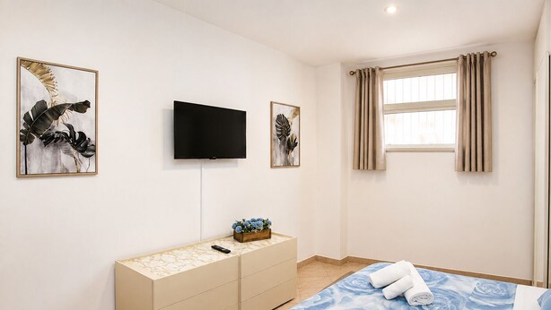 Ein Hotelzimmer mit Bett, Fernseher, Kommode und Bildern an den Wänden.