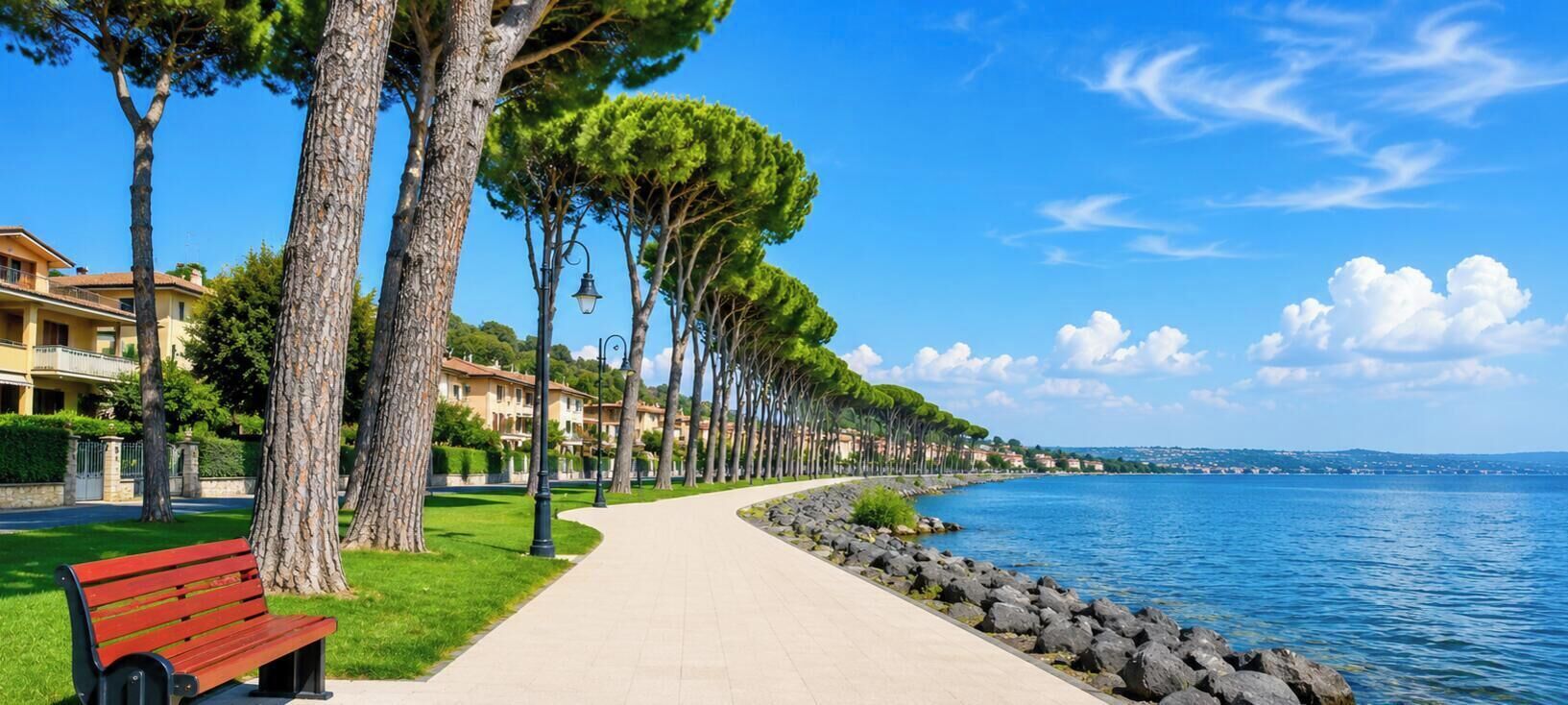 Una passeggiata costiera con un percorso lastricato, panchine e alberi che costeggiano il vialetto.