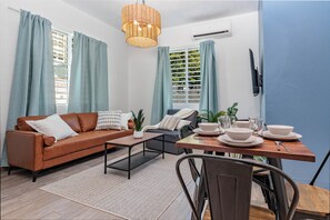 A modern living room with a sofa, coffee table, and dining table set.