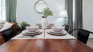 A dining table set with white plates, bowls, and a vase with a plant. - Apt B, Sunny San Juan Getaway (San Juan)