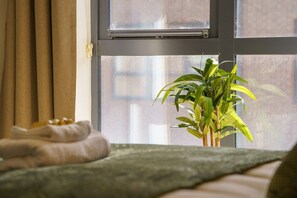 A bedroom with a bed, a window, and a potted plant. - Modern 2-bed central Swindon flat, 1 free parking (Swindon)