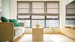 Ein modernes Wohnzimmer mit einer Couch, einem Couchtisch und einem großen Fenster mit Jalousien.