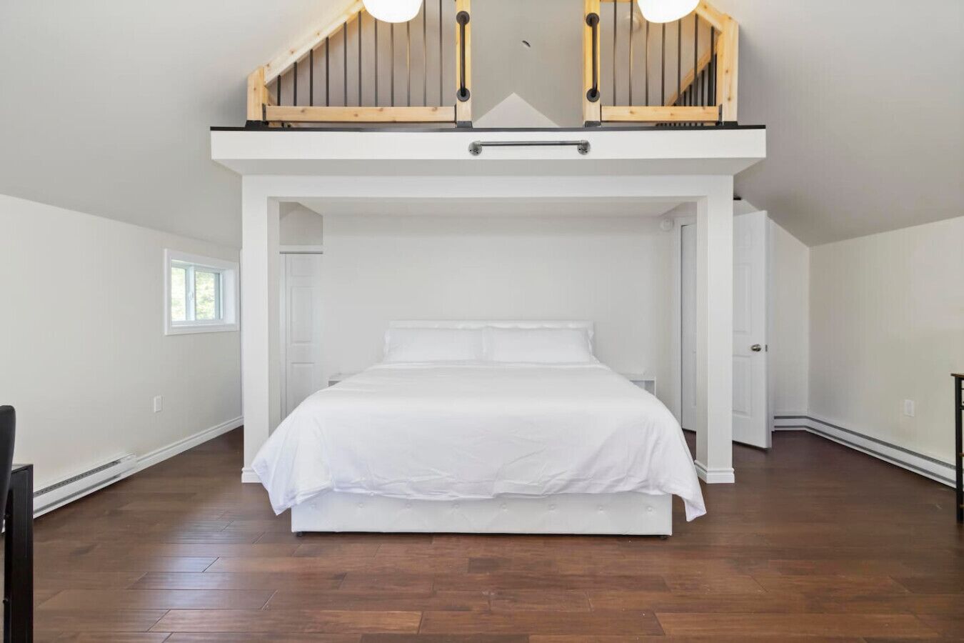 A bedroom with a loft-style bed, wooden beams, and a window.