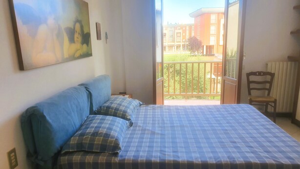 Una camera da letto con un letto, un quadro al muro, una finestra e vista su edifici.
