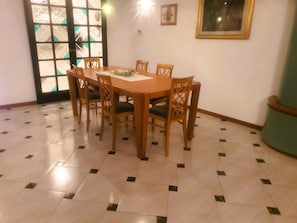 A dining area with a wooden table and chairs, a tiled floor, a door with glass panels, and a framed picture on the wall. - Elegant apartment in strategic location (Montelupo Fiorentino)