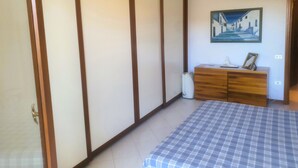 Una camera da letto con un letto, una cassettiera in legno, un quadro appeso e una porta scorrevole.