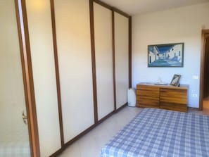 A bedroom with a bed, a wooden dresser, a painting on the wall, and a sliding door. - Elegant apartment in strategic location (Montelupo Fiorentino)