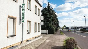 A building with a 'PENSION' sign, a paved sidewalk, and a road with vehicles. - Pension Greiser: Affordable accommodation in Leipzig (Leipzig)