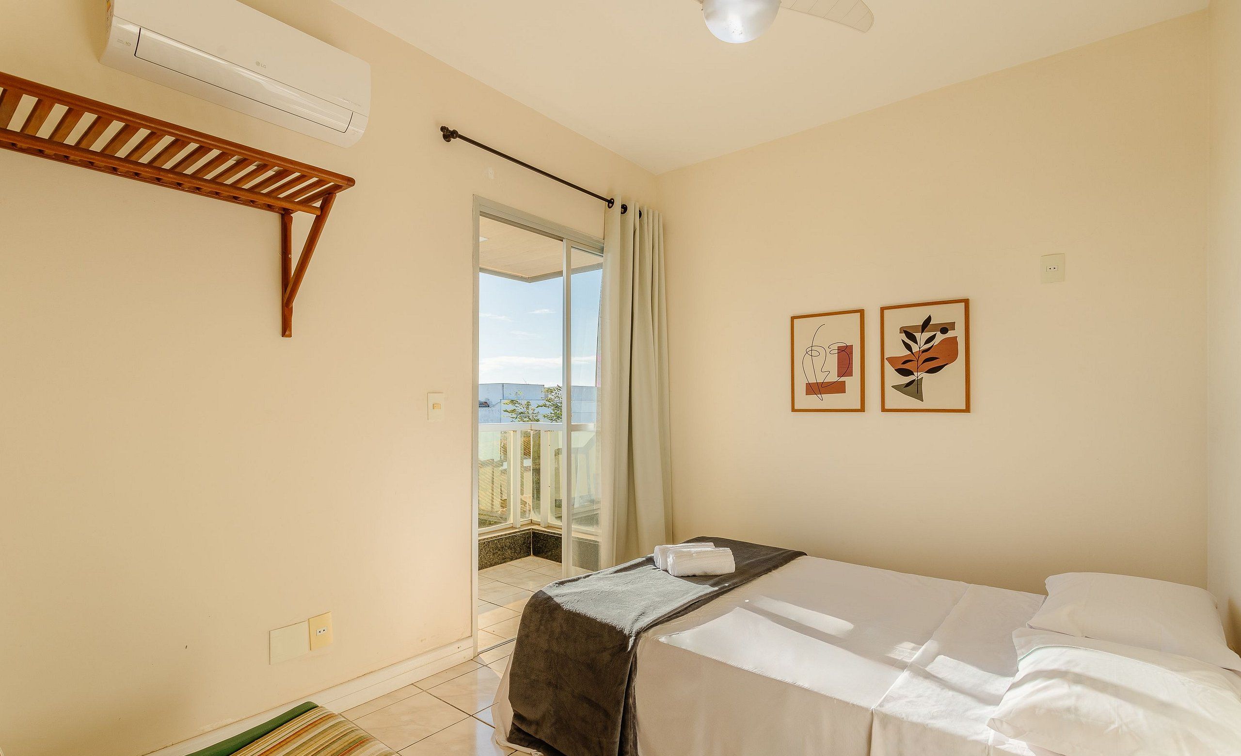Quarto com cama, prateleira de madeira, ventoinha no teto e vista para o exterior.