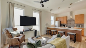 A modern living room with a flat-screen TV, leather armchair, and a sofa. - Modern Nashville Getaway Minutes From Downtown & Five Points Hearth and Hideout by Avantstay (Nashville)