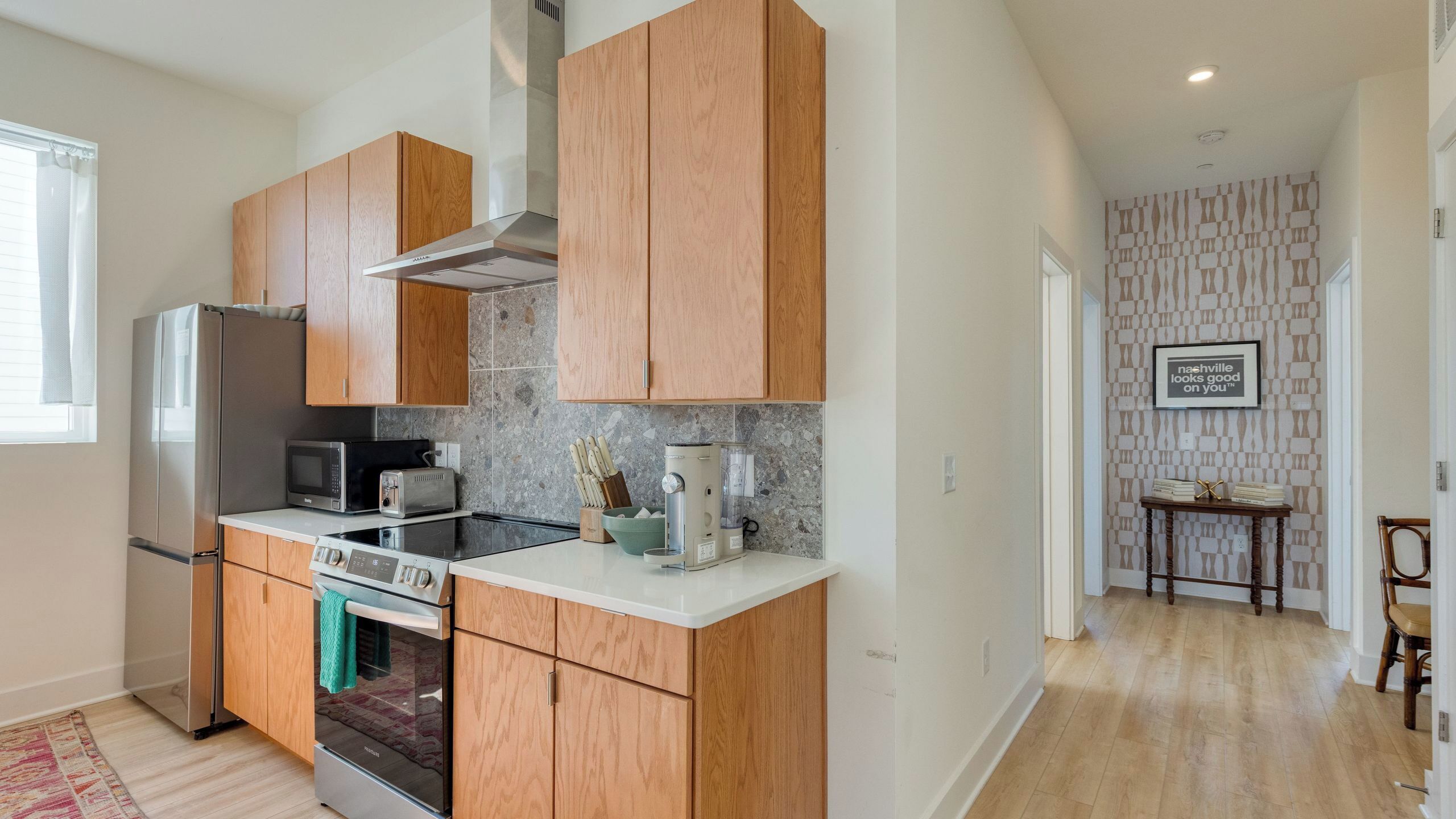 Eine moderne Küche mit Holzausstattung, Edelstahlgeräten und einer Steinrückwand.