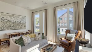 A living room with a sofa, armchair, dining table, and artwork. - Modern Nashville Getaway Minutes From Downtown & Five Points Hearth and Hideout by Avantstay (Nashville)