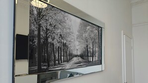 A framed black and white photograph of a tree-lined street, mounted on a wall with a mirror below it. - 2 bed Holiday Let-Contractors -Parking-Nr to hospital, Uni, City Centre, stadium (Sunderland)