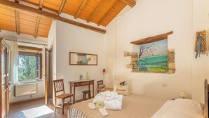 Ein Schlafzimmer mit einem Bett, einem Schreibtisch, Stühlen, einem Fenster und einem Bild an der Wand.