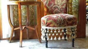 A chair with a floral pattern and a wooden table with a lattice base.