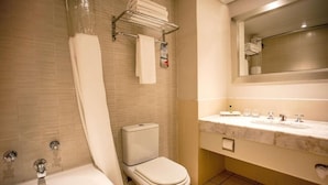 Un baño moderno con bañera, inodoro y tocador de mármol con lavabo y espejo.