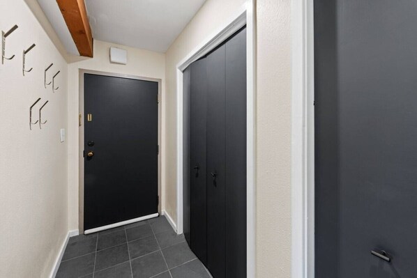 A hallway with two dark doors, a tiled floor, and a light-colored wall with a ceiling beam.