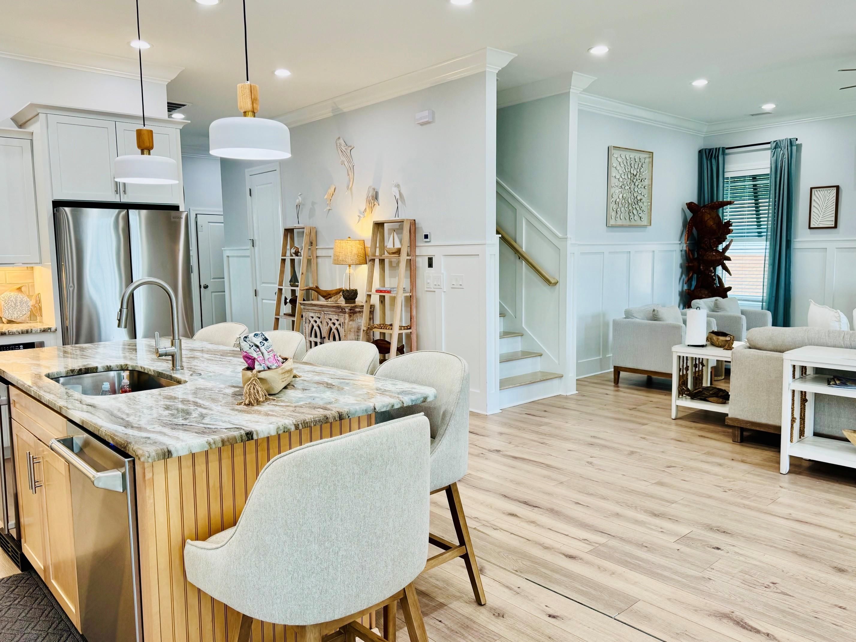 A modern kitchen with a central island, stainless steel appliances, and a dining area with a white table and chairs.