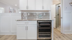 Eine Küche mit weißen Schränken, einem Edelstahlbackofen und einer gefliesten Spritzschutzwand.