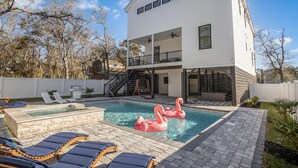Ein modernes, zweistöckiges Haus mit Swimmingpool, Liegestühlen und Whirlpool.