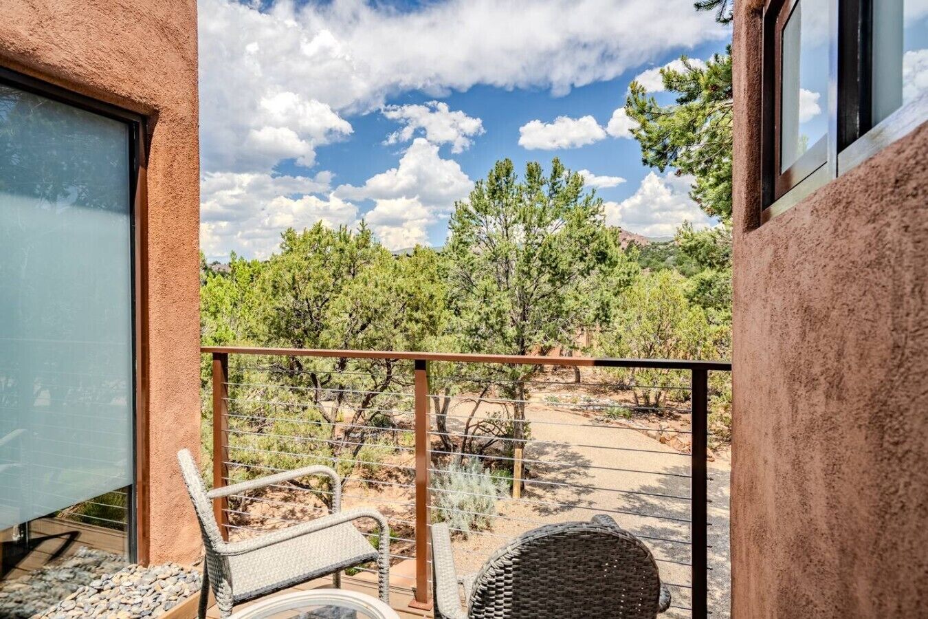 Un balcon offrant une vue sur un paysage désertique, avec des arbres et un ciel dégagé.