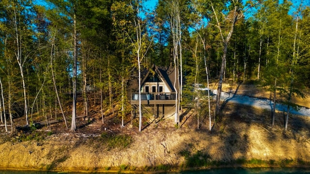 Une cabane au bord d’un lac, entourée d’arbres.