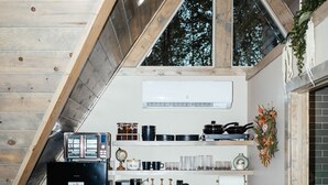 Une cuisine compacte avec un plafond en bois, une cuisinière intégrée et un petit coin repas comprenant une table et des chaises.