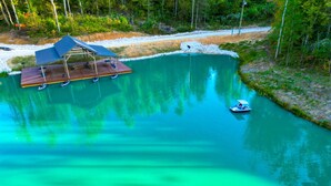 Un lago tranquilo con un muelle de madera y una zona de estar cubierta.