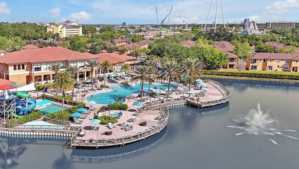 Ein Resort mit einem zentral gelegenen Schwimmbad, einer Wasserrutsche und einer Anlegestelle, die in einen See hineinreicht.