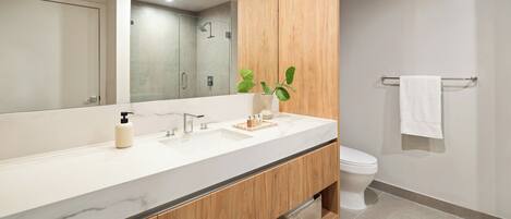 A modern bathroom with a wooden vanity, a large mirror, a white sink, and a toilet.