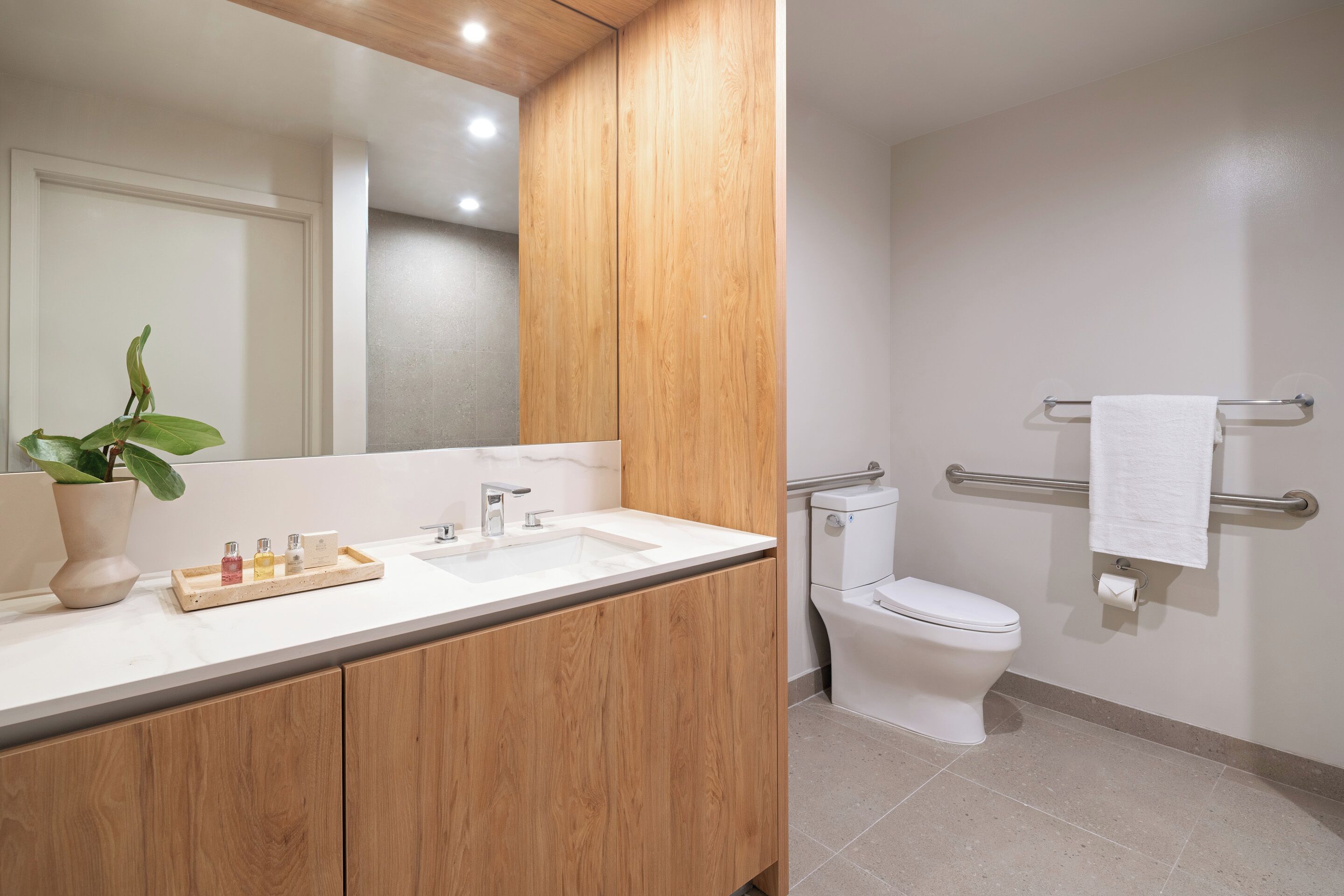 A modern bathroom with a wooden vanity, a white sink, and a toilet.