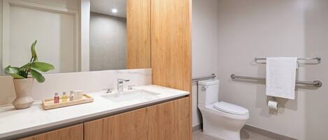 A modern bathroom with a wooden vanity, a white sink, and a toilet.