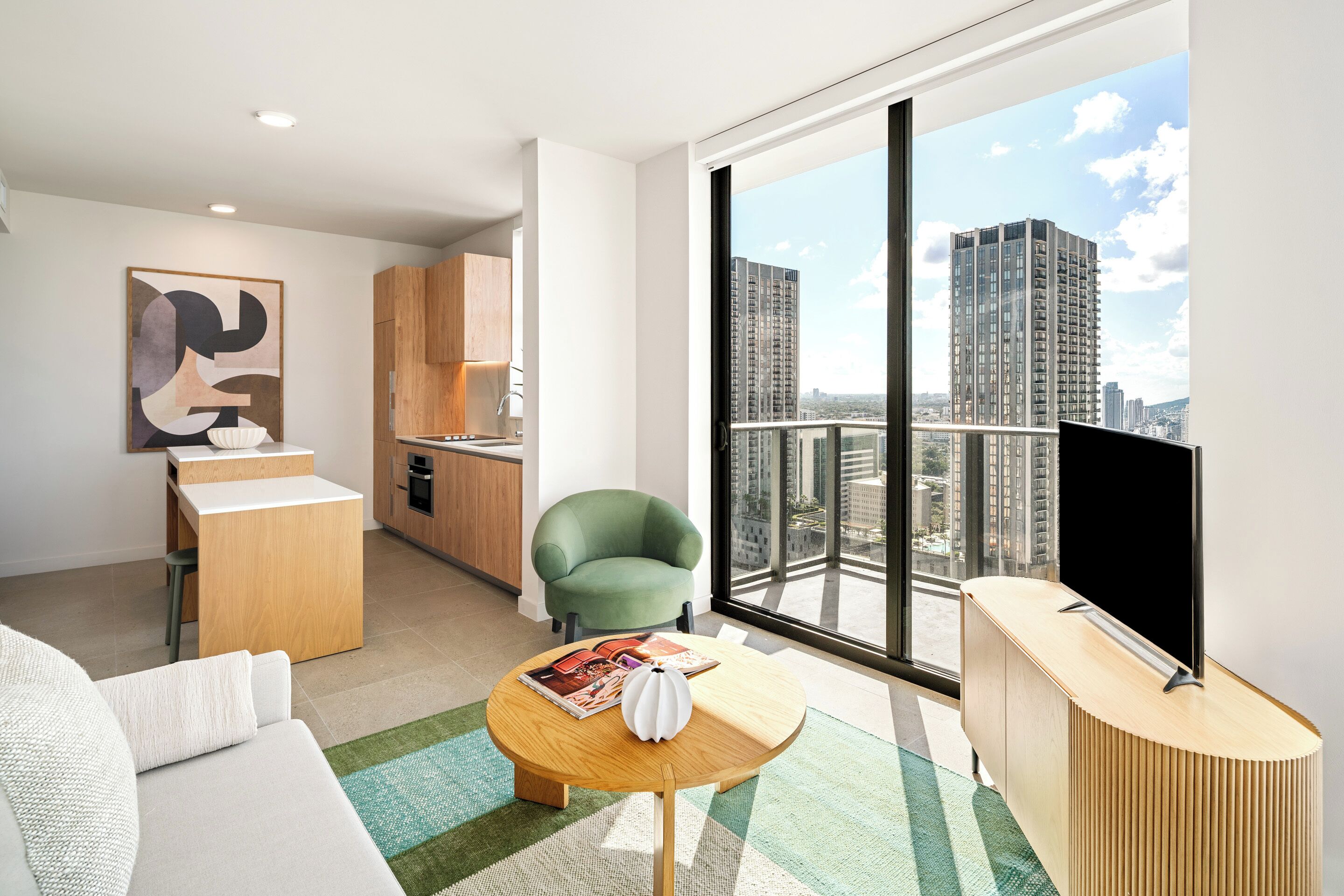 A modern apartment with a living area, a kitchen, and a large window offering a city view.