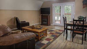 Una sala de estar con un sofá, una mesa de centro, una chimenea, un televisor y un comedor con sillas y una mesa.