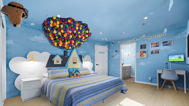 Ein Schlafzimmer mit einem Bett, einem Schreibtisch und einem Stuhl. Eine Wanddekoration zeigt ein Haus und Wolken.