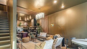 Una sala de estar moderna con una escalera, una zona de comedor y una cocina al fondo.