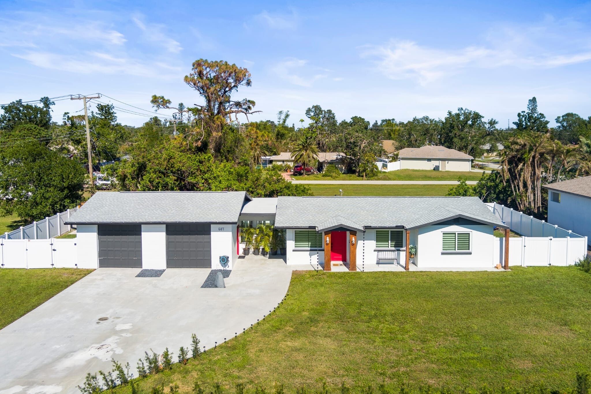 A modern two-story house with a garage, a red door, and a well-maintained lawn.
