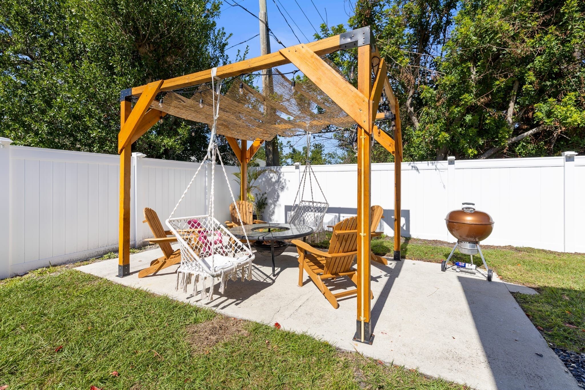 Un jardin avec une balançoire en bois, un barbecue et du mobilier d’extérieur.