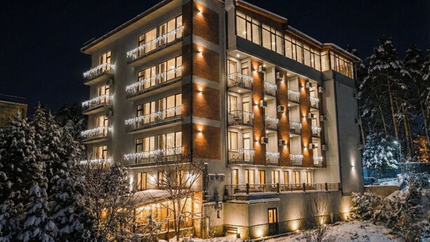 Un hotel de varios pisos con balcones, un patio central y alrededores nevados.