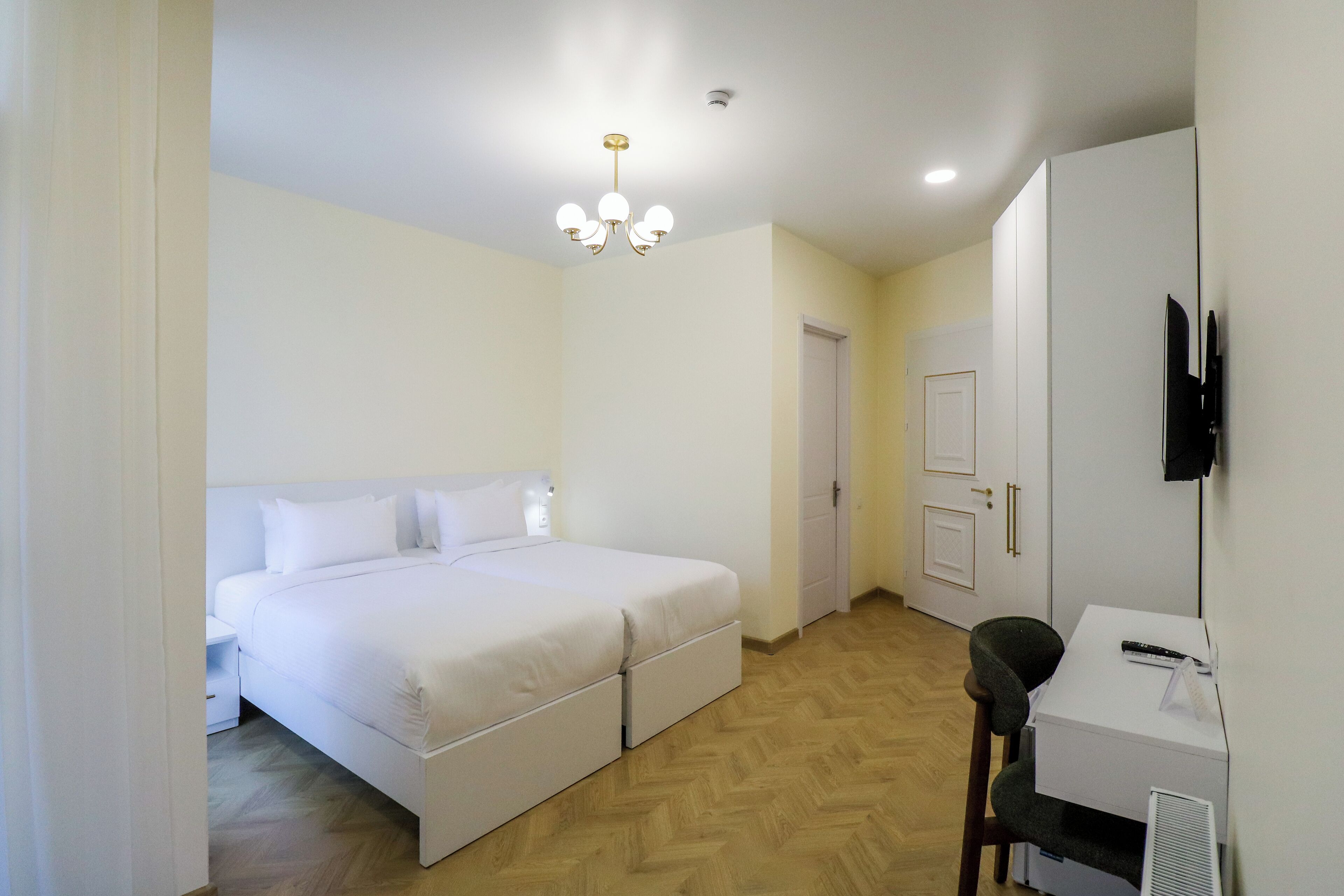 Un dormitorio con cama doble, escritorio, silla, armario y lámpara de techo.