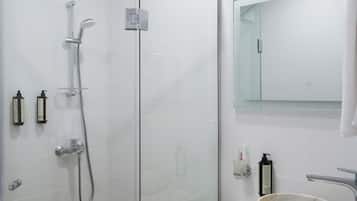 A modern bathroom with a glass-enclosed shower, a marble sink, and a large mirror.