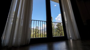 Una habitación con un gran ventanal corredero que da a un balcón con barandilla de metal.