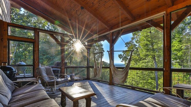 A covered outdoor seating area with wooden furniture, a table, and a hammock. - Pop`s Peak| Morganton, GA (Morganton)