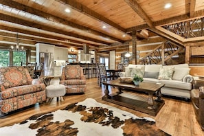 A spacious living area with a wooden ceiling, a dining area, and a kitchen with white cabinets.