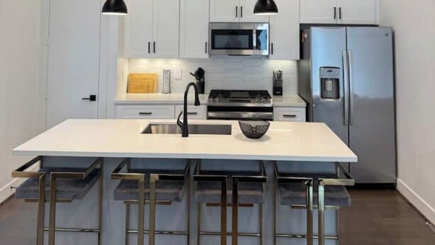 A modern kitchen with a central island, stainless steel appliances, and bar stools. - Cozy & Luxury 3BR for Families, Nurses & Groups (Houston)