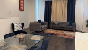 Een moderne woonkamer met een glazen eettafel, twee banken en een kamerkleed met een patroon.