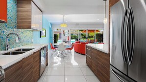 A modern kitchen with a stainless steel refrigerator, wooden cabinets, and a tiled backsplash. - 2-bedroom condo in Historic Tennis Club (Palm Springs)