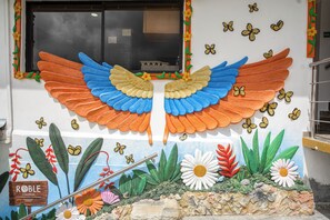 A mural with a large wing design, a sign reading "ROBLE COLONIAL," and various flowers and butterflies. - ROBLE COLONIAL  (Guatape)